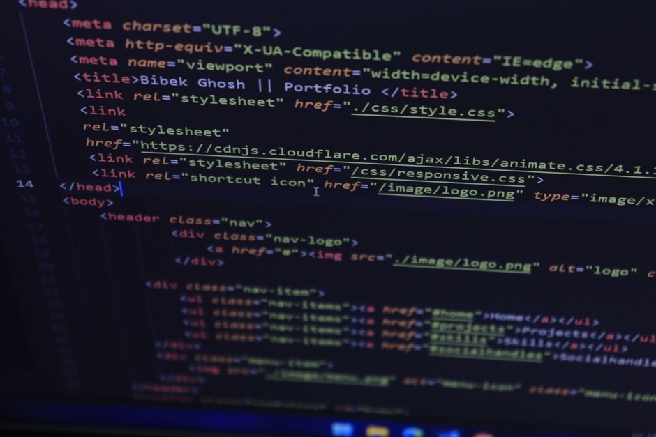 A detailed close-up of a computer screen displaying HTML code with colorful syntax highlighting, including tags and attributes related to web development. The code contains various elements such as <h